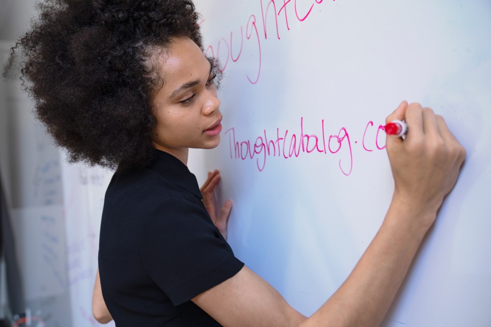 Eine junge Frau schreibt auf ein Whiteboard.