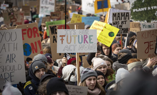 Junge Menschen demonstrieren mit Plakaten für den Klimaschutz