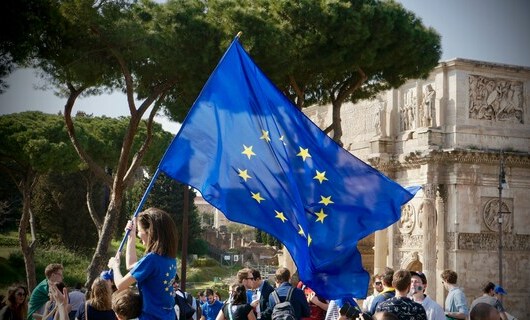 Eine junge Person mit einer Europaflagge vor einer Menschenmenge