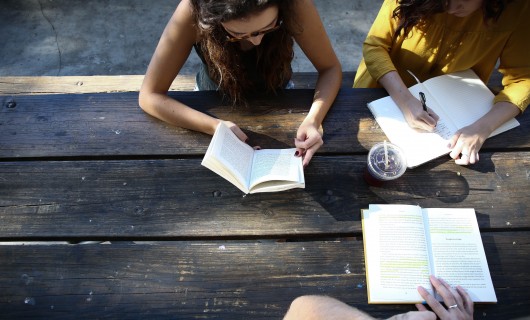 Drei Jugendliche sitzen an einem Tisch und lesen und schreiben