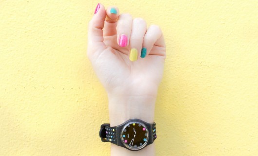 Hand mit lackierten Fingernägel und einer schwarzen Armbanduhr
