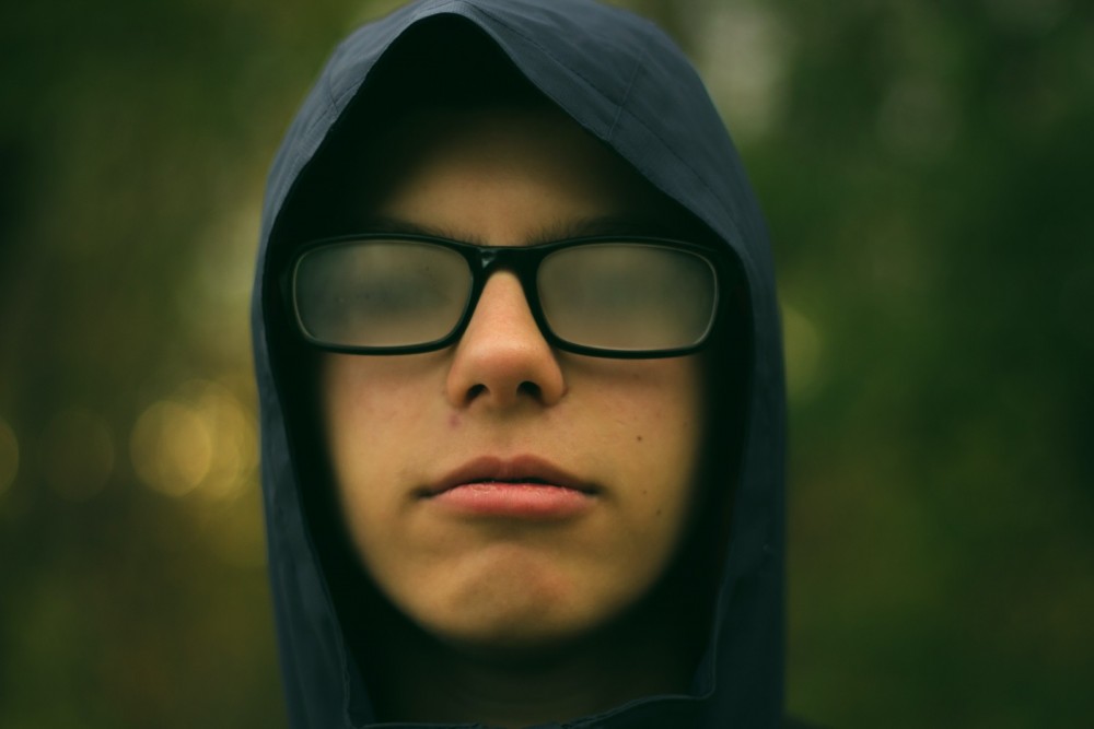 Ein Junge mit beschlagener Brille und Kapuze auf dem Kopf.