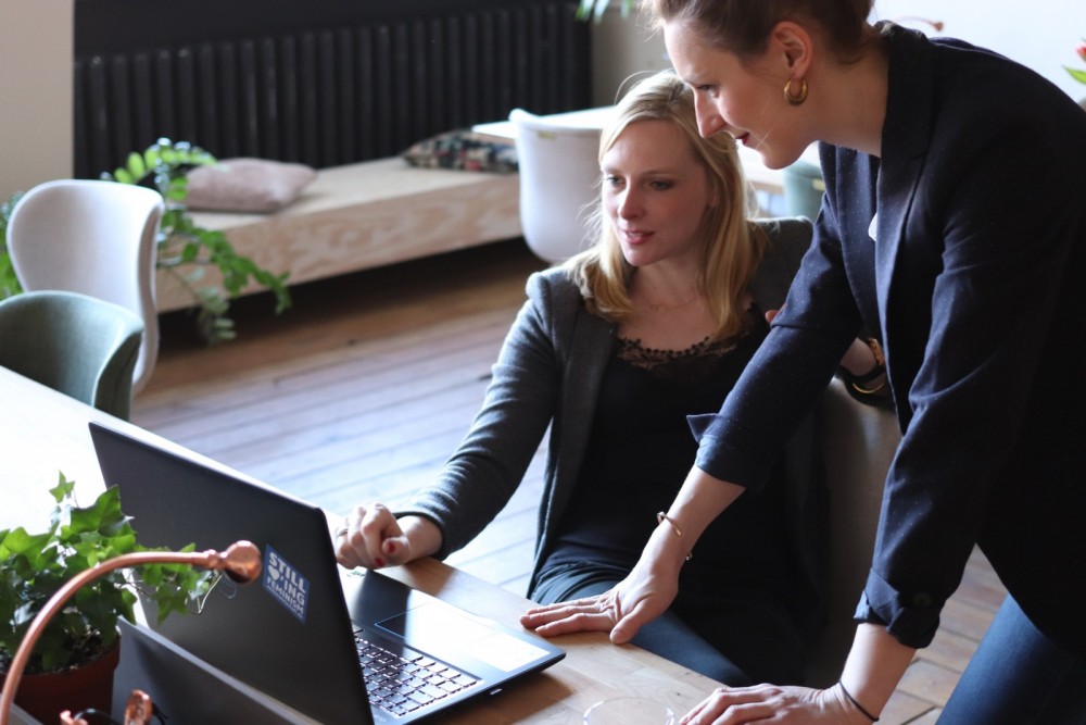 Zwei Frauen schauen zusammen auf einen Laptop.