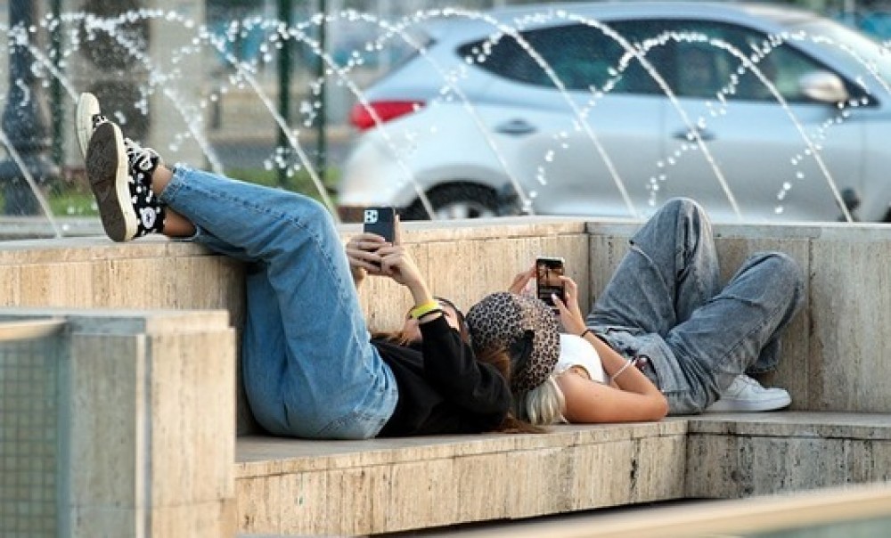 Zwei Personen liegen auf einer Bank und schauen auf ihre Smartphones (Foto: Surprising_Media via pixabay.com)