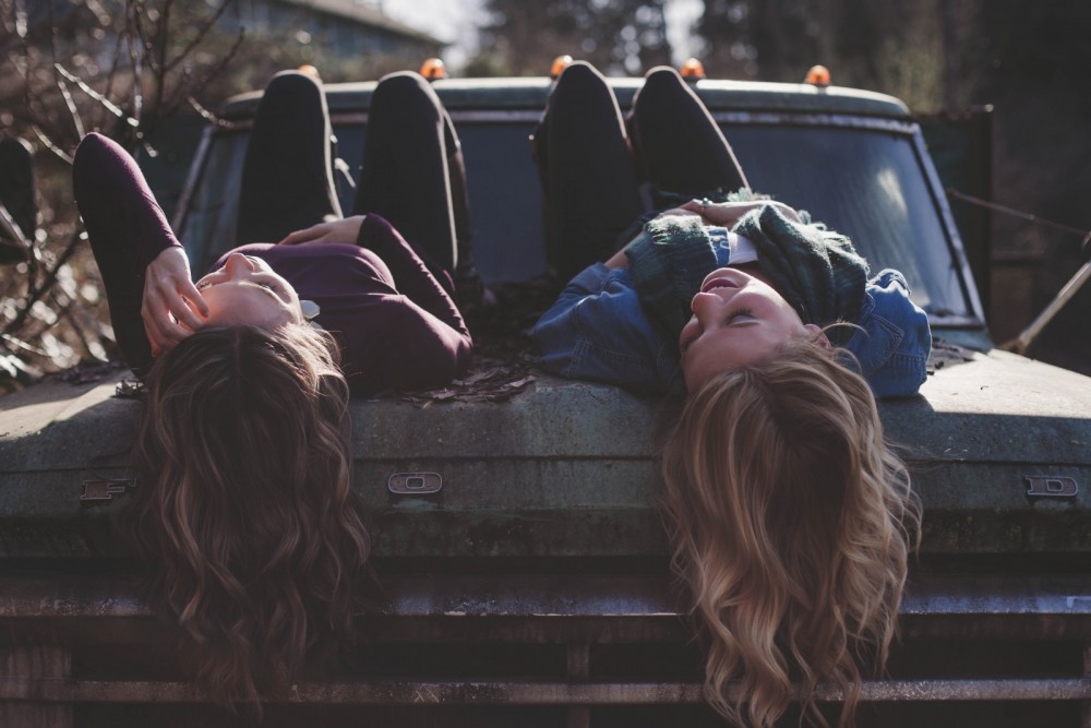 Zwei Frauen liegen in der Sonne auf dem Dach eines Autos.