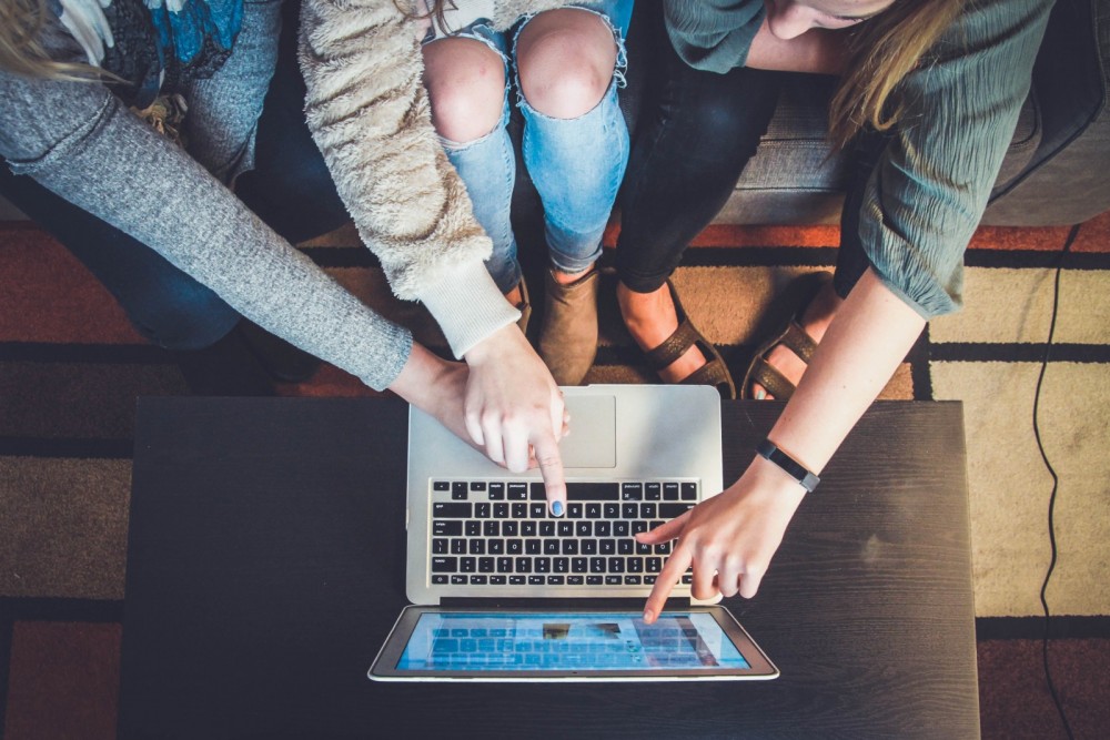 3 Frauen zeigen mit ihren Fingern auf einen Laptop.