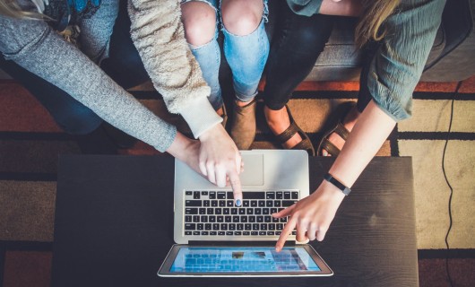 3 Frauen zeigen mit ihren Fingern auf einen Laptop.