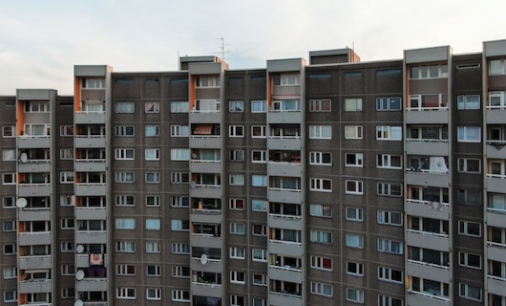 Ein Hochhaus mit grauer Fassade und weißen Balkonen. Foto: M. Lenk via unsplash.com