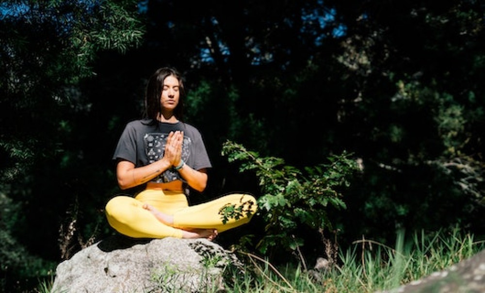 Frau meditiert sitzend auf einem Stein