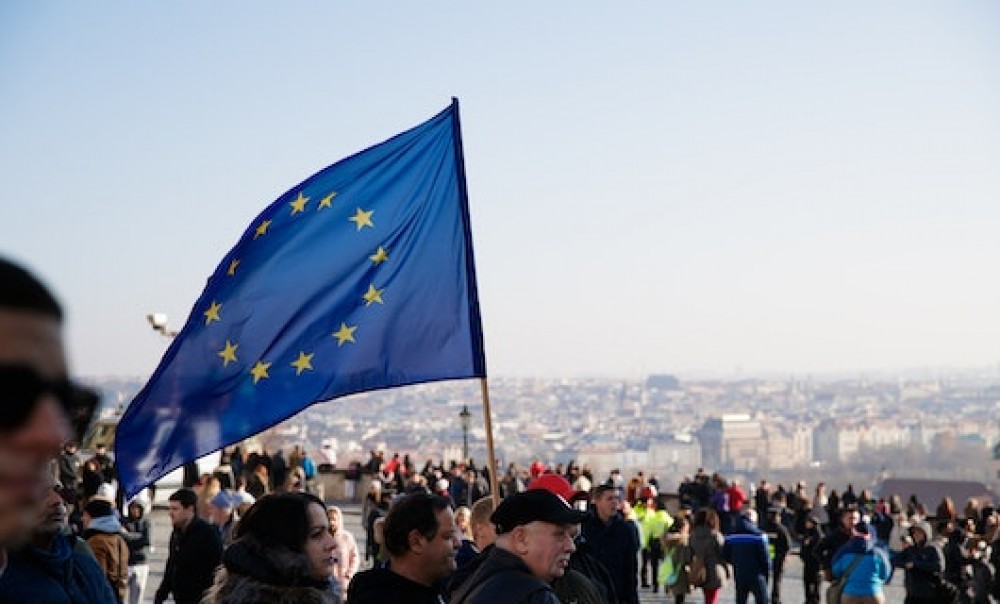 Menschenversammlung auf einem Platz mit europäischer Flagge