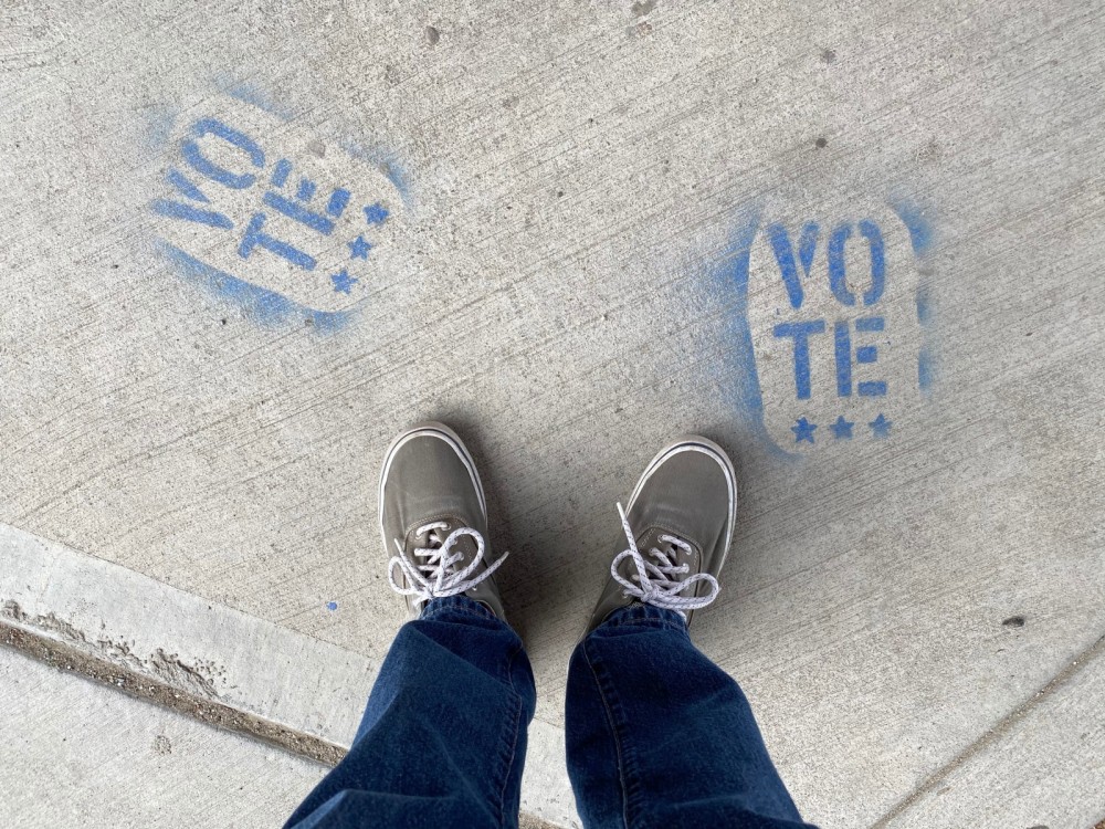 Blaue Sneakers stehen auf dem Boden neben dem Schriftzug vote.